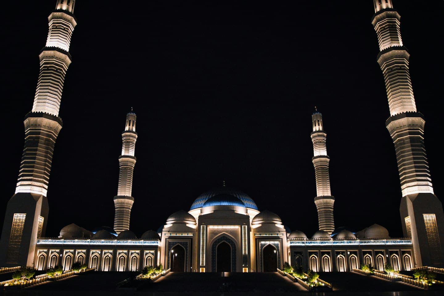 The grand mosque with illuminated minarets stands at night.