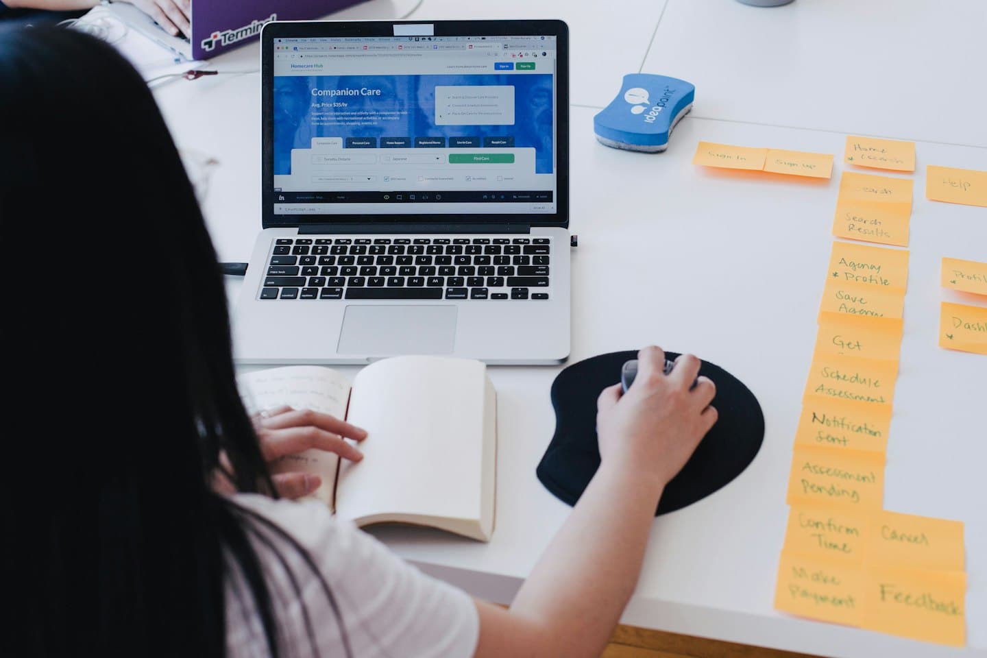 Person working on laptop with sticky notes on desk.